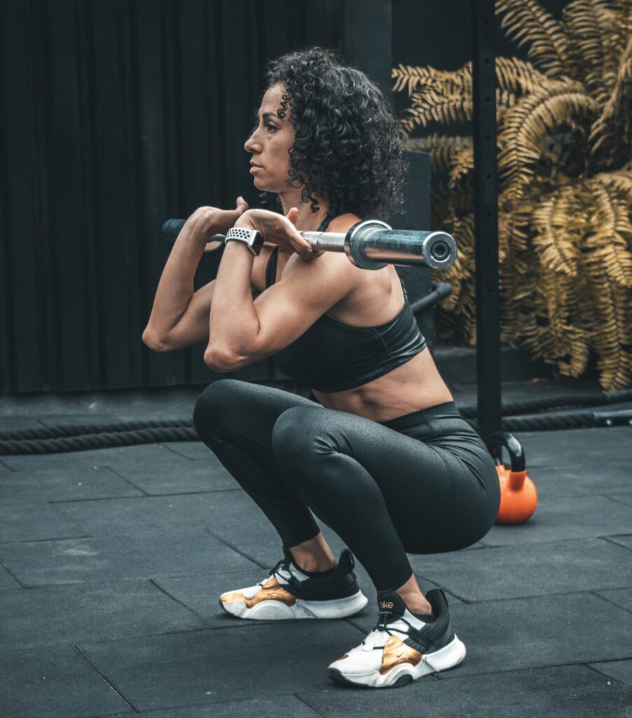 Fit woman doing barbell squats in a gym setting, focused on strength training.