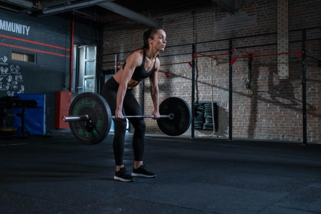 A determined woman performing deadlifts in a modern gym environment, showcasing strength and fitness.